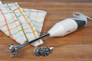 The Bamix Pro-2 G200 Professional Series Immersion Hand Blender on a maple butcher block table with a kitchen towel.