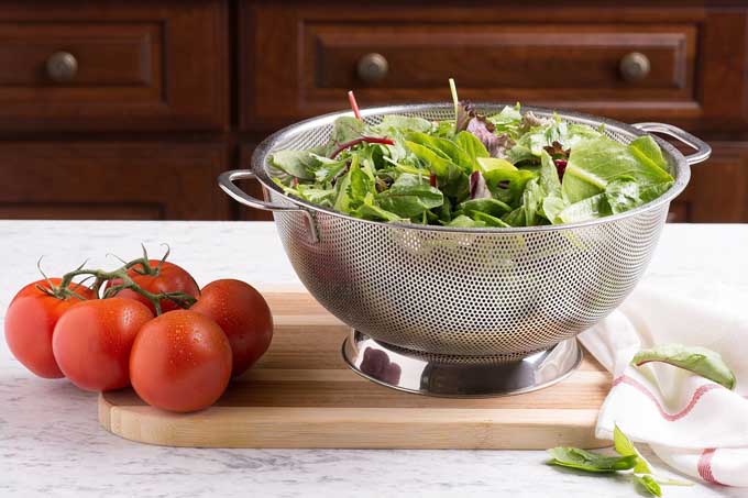 Bellemain Micro-perforated Stainless Steel 5-quart Colander with lettuce and tomatoes.