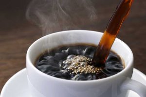 A white coffee cup with liquid being poured in.