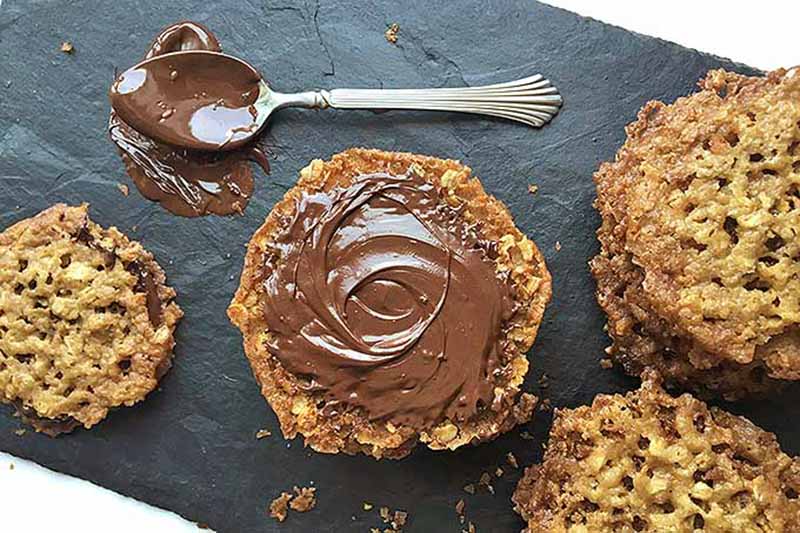 Image of spreading chocolate on lace-like baked goods on a slate.