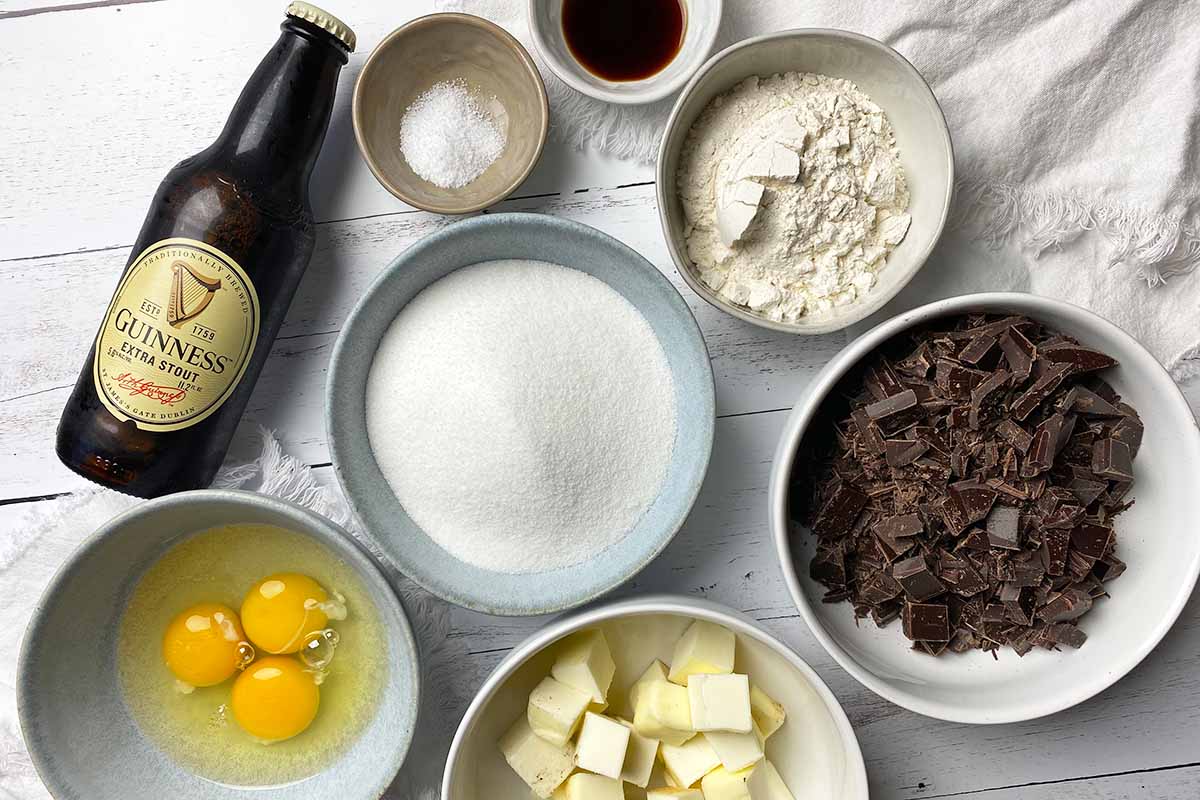 Horizontal top-down image of assorted wet and dry ingredients prepped in bowls next to a bottle.