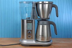 The Breville BDC450 Precision Brewers sitting on a maple butcher block table with a blue painted wooden background.