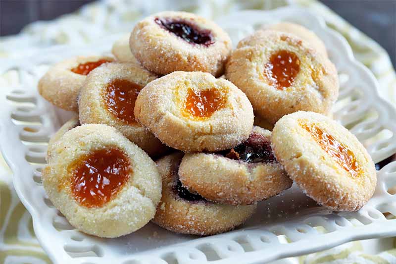 Jam-filled thumbprint cookies on a square white serving dish.