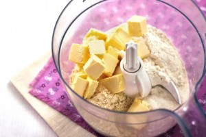 food processor with baking ingredients inside sitting on purple mat