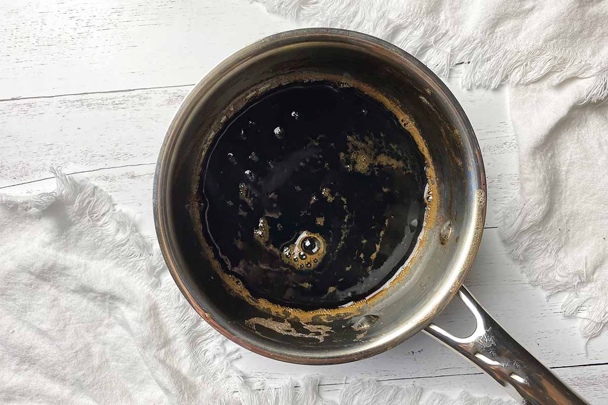 Horizontal image of a reduced, dark brown liquid in a small pot.