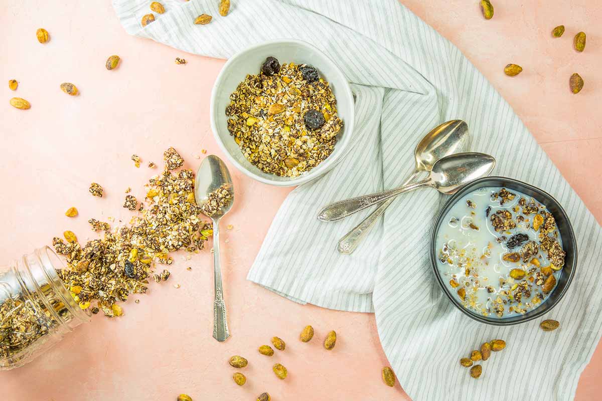 Horizontal image of chocolate granola in bowls on a towel, next to a jar of poured granola.