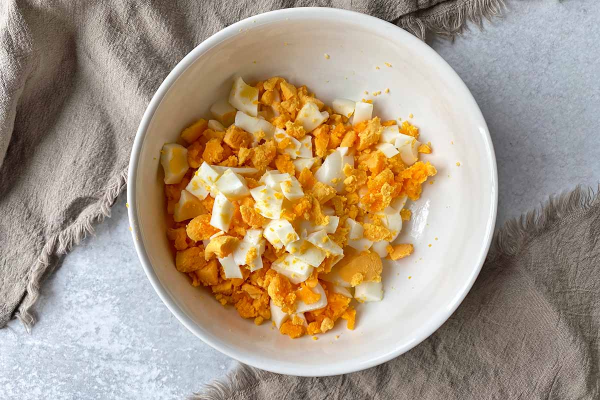 Horizontal image of chopped hard-boiled eggs in a large bowl.