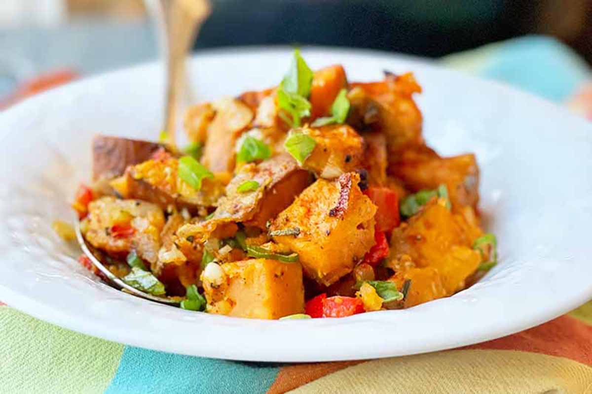 Horizontal image of a sweet potato hash on a white plate.
