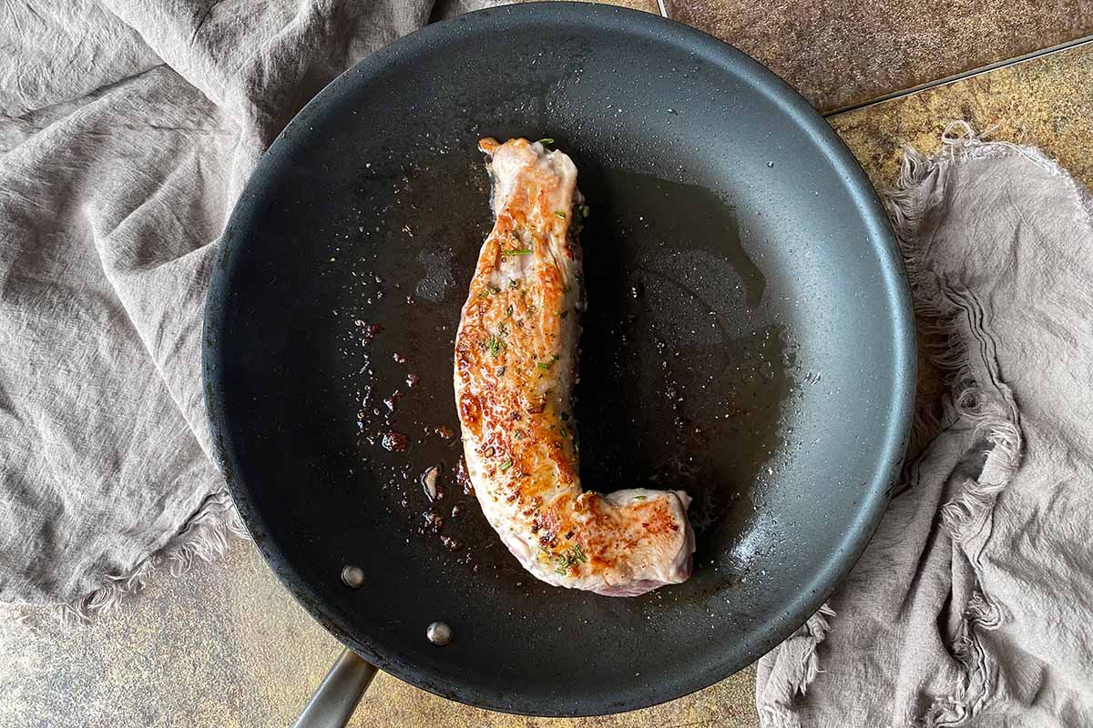 Horizontal image of a seared piece of meat in a skillet.