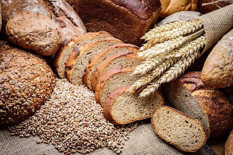 Horizontal image of assorted breads on a wooden surface.