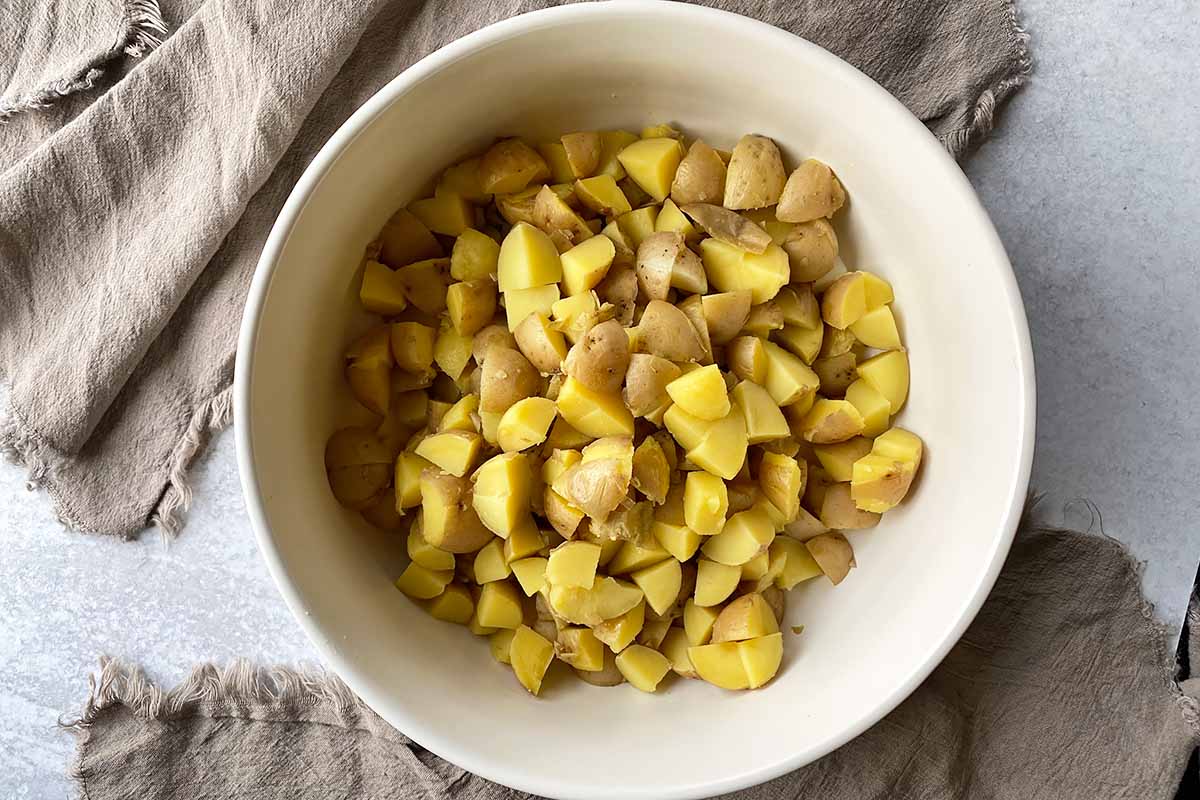 Horizontal image of cubed boiled golden potatoes in a large bowl.