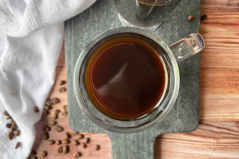Horizontal image of a dark brown beverage in a glass mug.