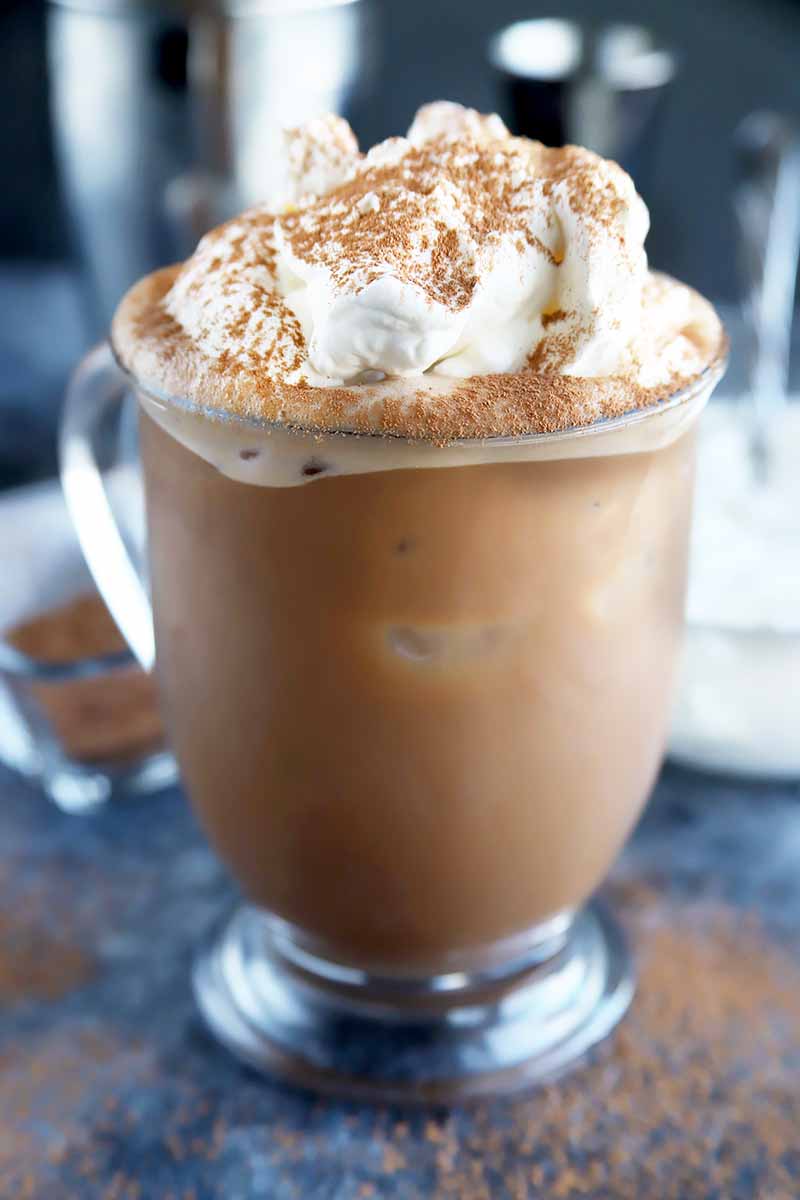 Vertical image of a glass of a coffee drink topped with whipped cream.