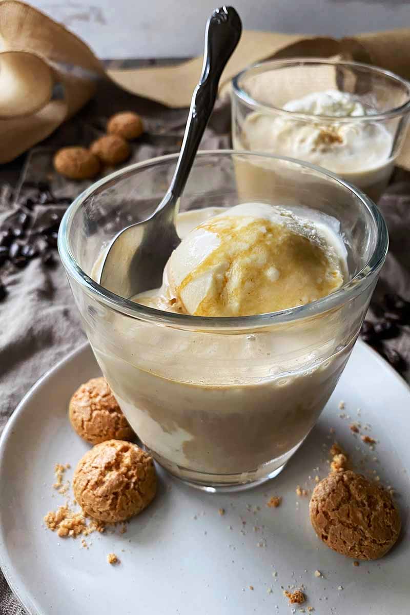 Vertical image of two glasses with espresso and ice cream on plates with cookies.