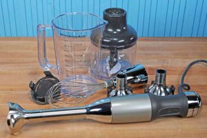The motorized based and all of the attachments and accessories of the KitchenAid KHB2561 laying on a maple butcher block surface.