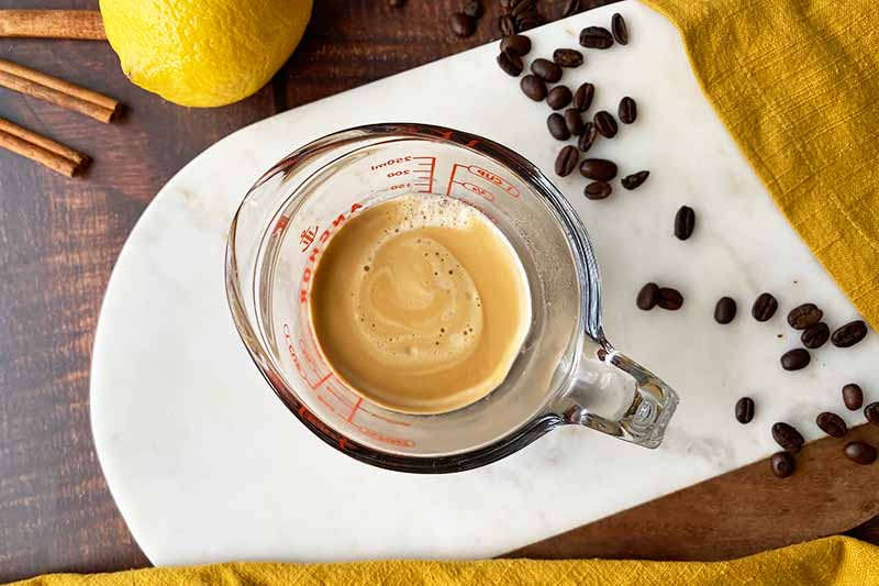 Horizontal image of hot coffee in a liquid measuring cup.