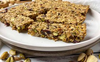 Horizontal image of oat, nut, and dried fruit snacks on plates.