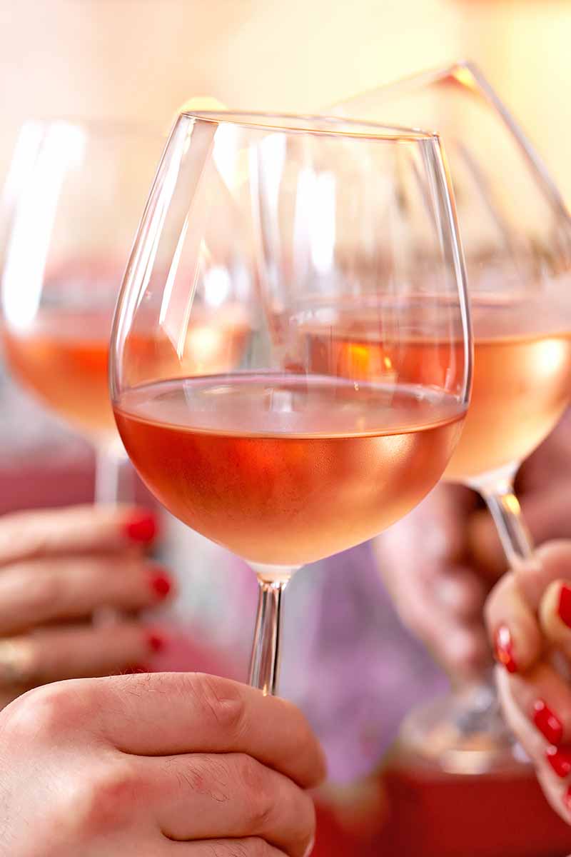 Vertical close-up image of chilled drinkware toasting.