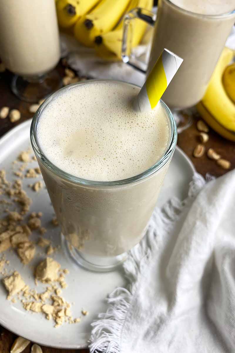 Vertical image of the top of a creamy beverage in a glass mug topped with a yellow straw.