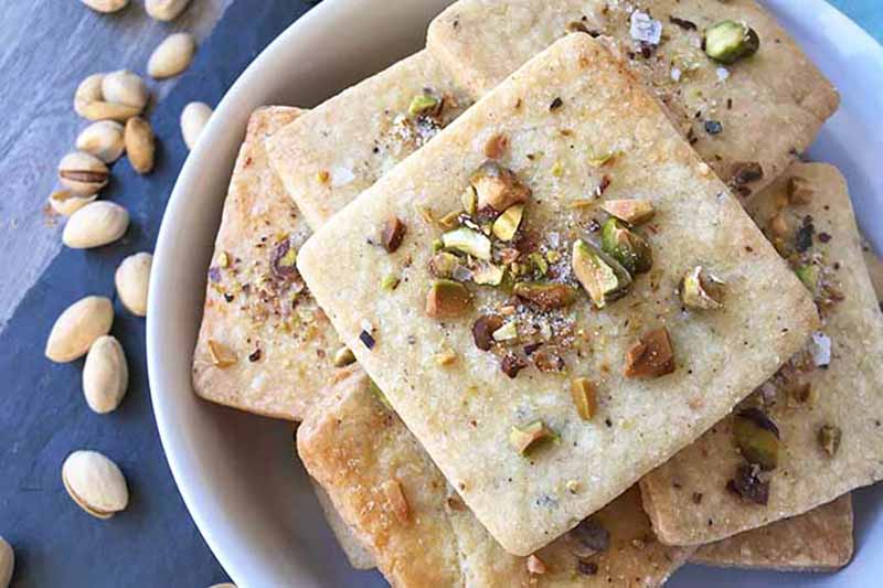 Horizontal image of square-shaped baked goods with nuts on top.
