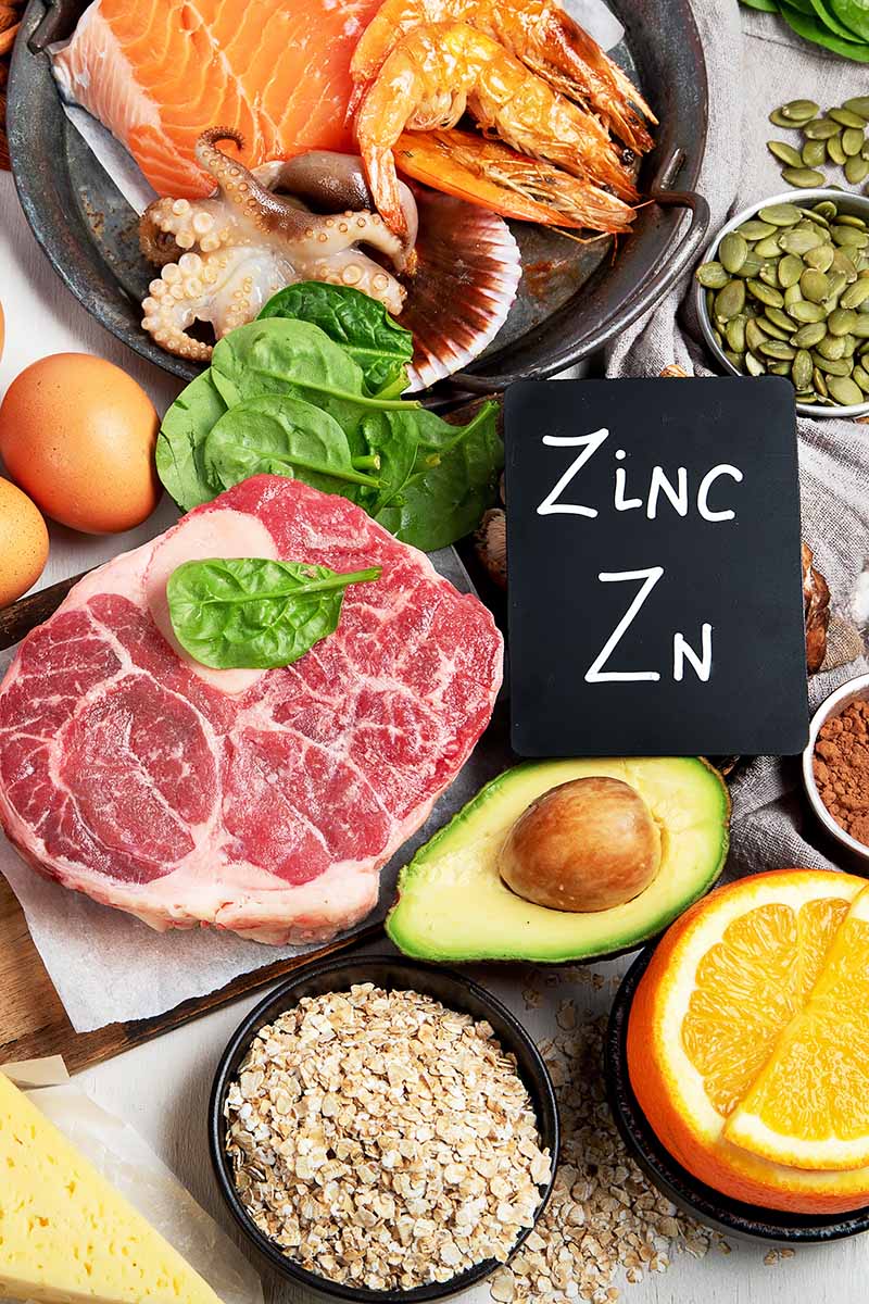Vertical image of assorted fresh and healthy food ingredients next to a chalkboard sign.