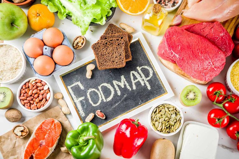 Horizontal image of assorted fresh and healthy food items surrounding a chalkboard.