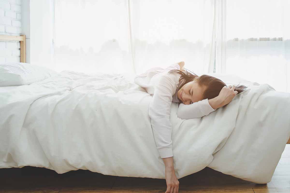 Horizontal image of an unwell woman in bed.